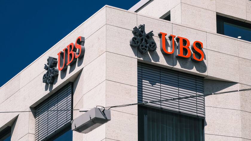Rotes UBS Logo an zwei Ecken von einem beigen Gebäude.