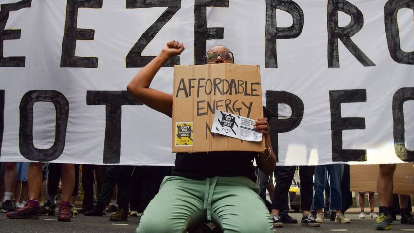 August 26, 2022, London, England, United Kingdom: A protester sits on the road in front of a group of protesters blocking the traffic. Crowds gathered outside Ofgem Office of Gas and Electricity Markets in Canary Wharf in protest against the huge energy price increases. Energy companies have posted record profits while gas and electricity bills in the UK have skyrocketed. London United Kingdom - ZUMAv130 20220826_zip_v130_049 Copyright: xVukxValcicx