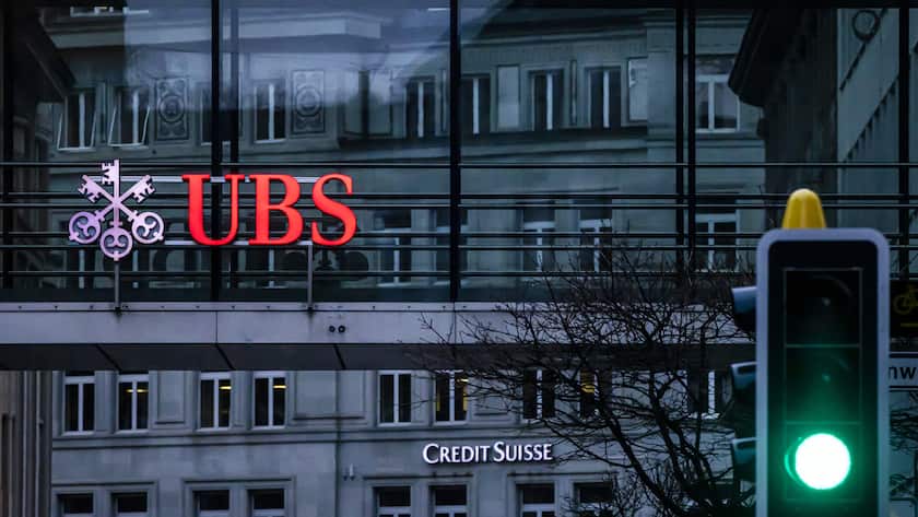 The logos of the Swiss banks Credit Suisse and UBS are displayed on different buildings behind traffic lights in Zurich, Switzerland on Sunday March 19, 2023. (KEYSTONE/Michael Buholzer).