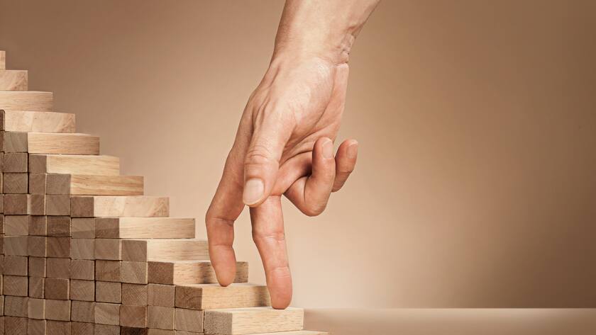 Eine Hand fährt über eine kleine Holztreppe