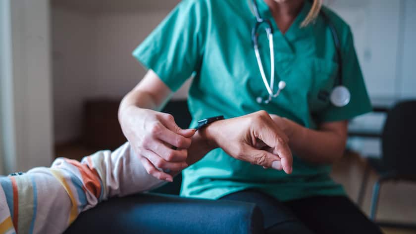 Smartwatch for health care. A woman from the medical health system wears a smartwatch for remote monitoring of vital signs on an elderly person - assisted living concept