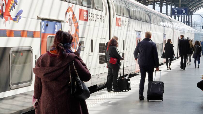Menschen von hinten laufen auf SBB Doppelstockzug zu am Bahnhof Luzern.