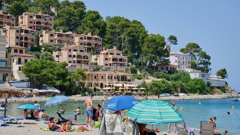 Port de Soller, Mallorca - August 13, 2021: Port de Soller beach with sun bathing people in front, Mallorca LicenseRM beach of Port de Soller in Mallorca LIC:RM