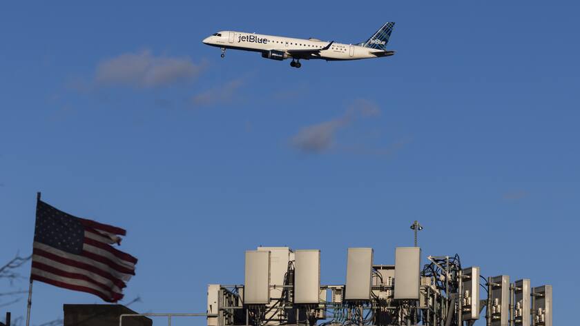epa09693909 A JetBlue airways airplane (Embraer E190AR, tail number N236JB) on approach to land at LaGuardia Airport passes telecommunications antennae on a rooftop in the Queens borough of New York, New York, USA, 18  January 2022. Telecommunication…