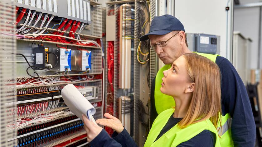Two electricians with plan looking at fuse box model released Symbolfoto property released ZEDF03237
