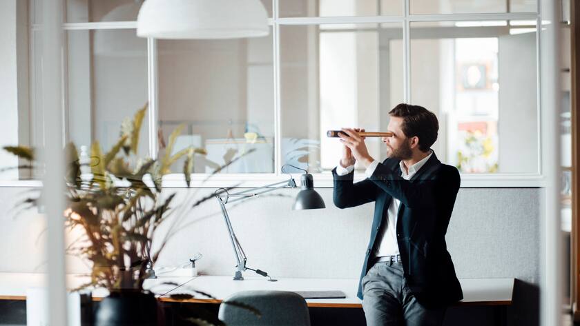 Male entrepreneur looking through binoculars while sitting on desk model released Symbolfoto property released GUSF06012