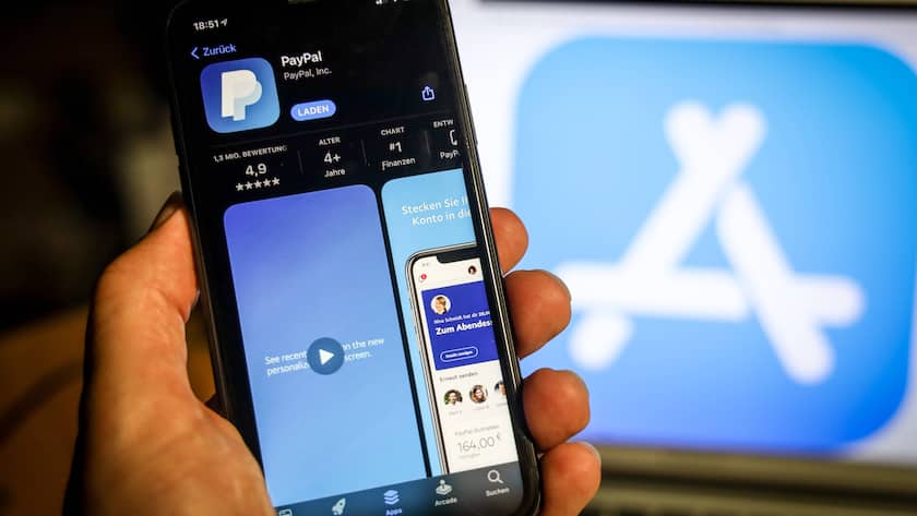 Paypall App auf einem Handy im Hintergrund ist das Applestore-Symbol auf einem Bildschirm zu sehen.