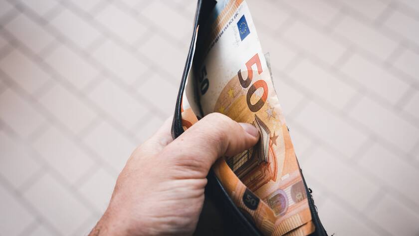 50 Euroschein in einem schwarzen Portemonnaie in einer Männerhand.