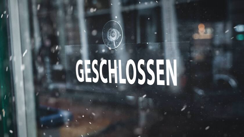 Schild an einem Schaufenster im Winter bei Schneefall mit der Aufschrift: Geschlossen. Restaurant, Geschäft oder Bar nicht geöffnet