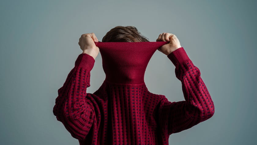 Mann zieht Pullover über seinen Kopf