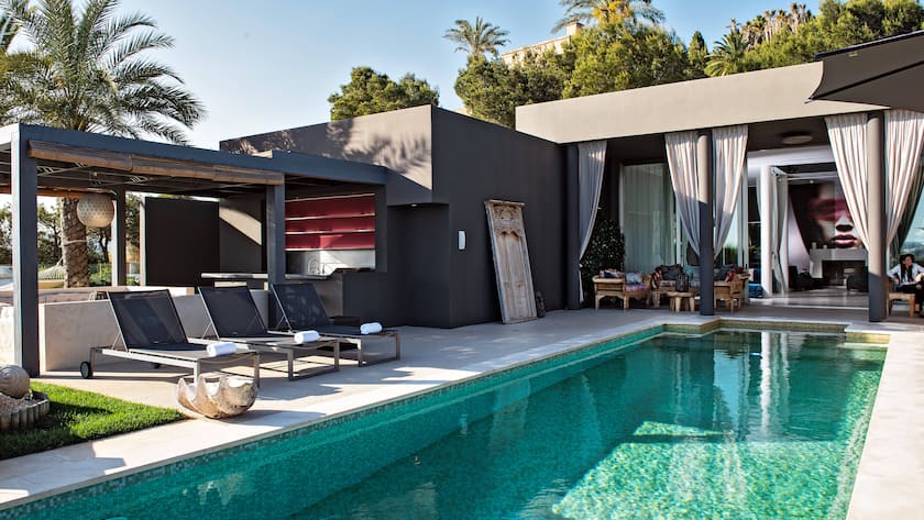 Aus dem grosszügigen Living Room führt der Weg zum Poolbereich mit Blick auf Ibiza-Stadt und aufs offene Meer. Die früher grellweiss gestrichenen Wände hüllte Anja Graf in dunkle Töne.