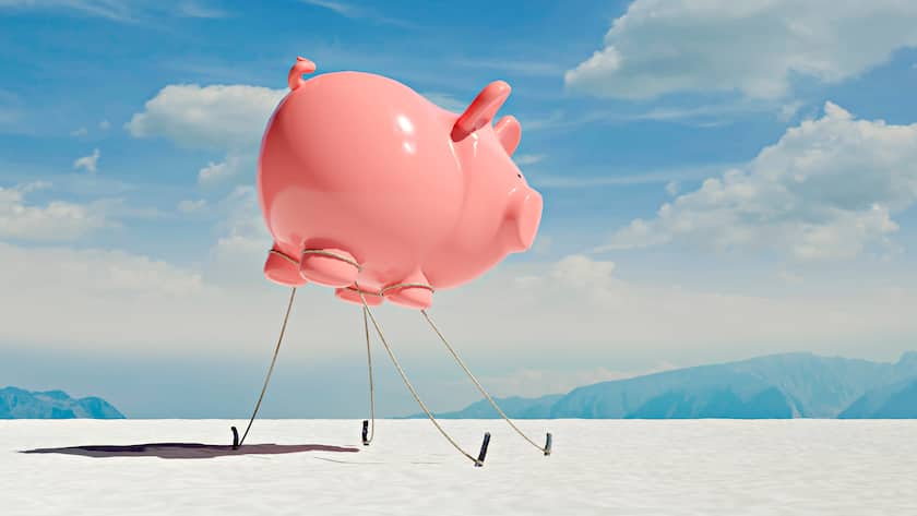 Three dimensional render of floating piggy bank tied down to ground in desert, VTF00666