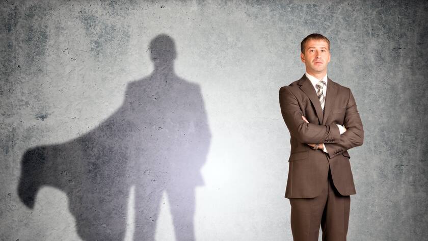 Geschäftsmann mit Supermann-Schatten schaut in die Kamera