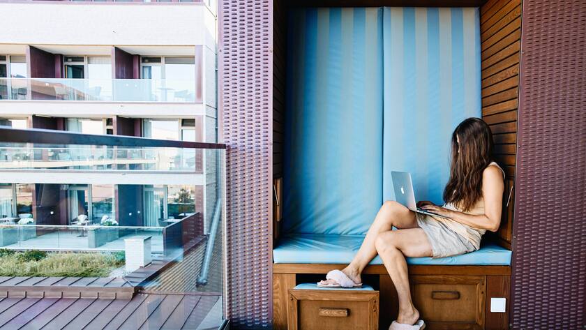 Woman with notebook and handy working in a beach chair as digital nomad and workaholic on July 03, 2022 in Wyk, Föhr Island, Germany. MODEL RELEASED