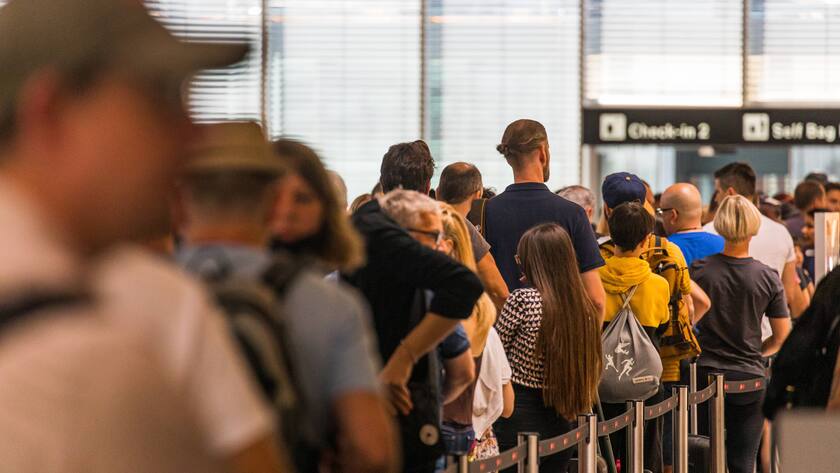 Reisende stehen an einem Check-In Schalter am Zürich Flughafen an.