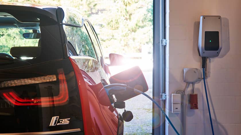 Ein Elektroauto BMW i3 beim Laden an der Wallbox zuhause in der Garage, Lichtreflex E-Auto aufladen