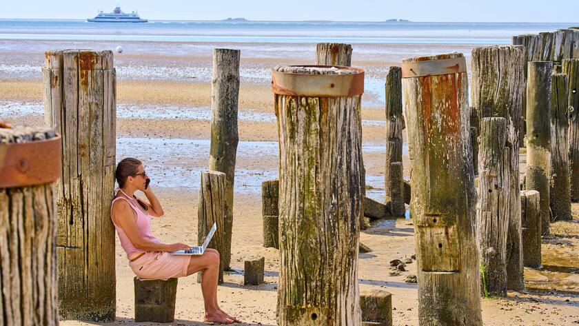 Woman with notebook and handy working as digital nomad and workaholic on July 03, 2022 in Wyk, Föhr Island, Germany. MODEL RELEASED