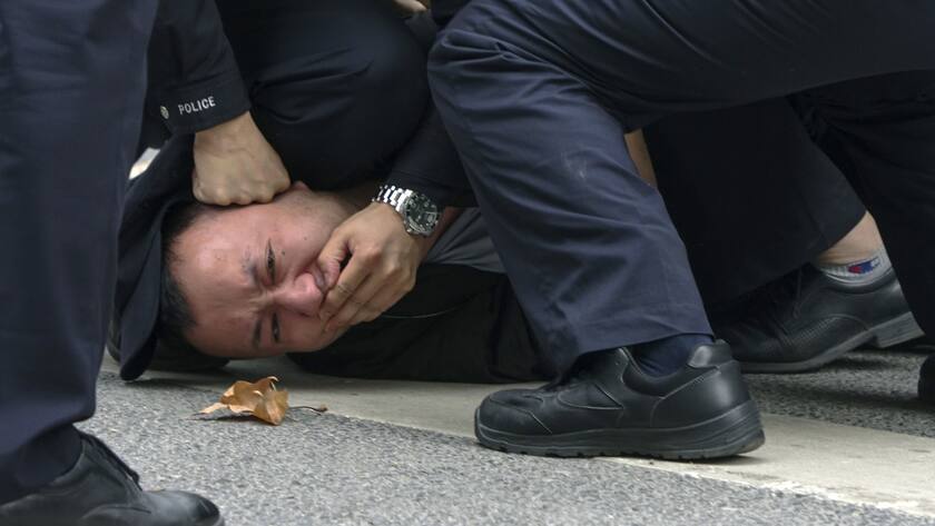 In this photo taken on Sunday, Nov. 27, 2022, policemen pin down and arrest a protester during a protest on a street in Shanghai, China. Authorities eased anti-virus rules in scattered areas but affirmed China's severe "zero- COVID" strategy Monday after crowds demanded President Xi Jinping resign during protests against controls that confine millions of people to their homes. (AP Photo)