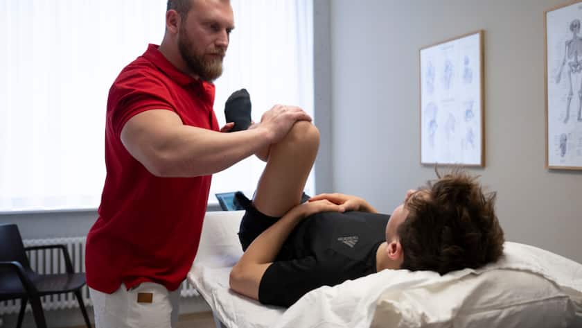 Die Branche "Gesundheits- und Sozialwesen" beschäftigte im 2024 die meisten Erwerbstätigen: Ein Therapeut bewegt das Knie eines Patienten im Behandlungsraum (Symbolbild).