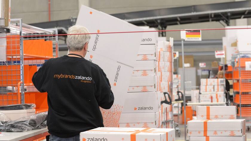 Ein Zalando-Mitarbeiter in Rückensicht faltet einen Zalando-Karton.