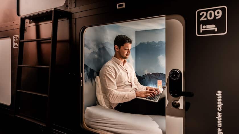Ein Mann sitzt in einem der 144 Kapseln des Capsule Hotel Alpine Garden am Flughafen Zürich