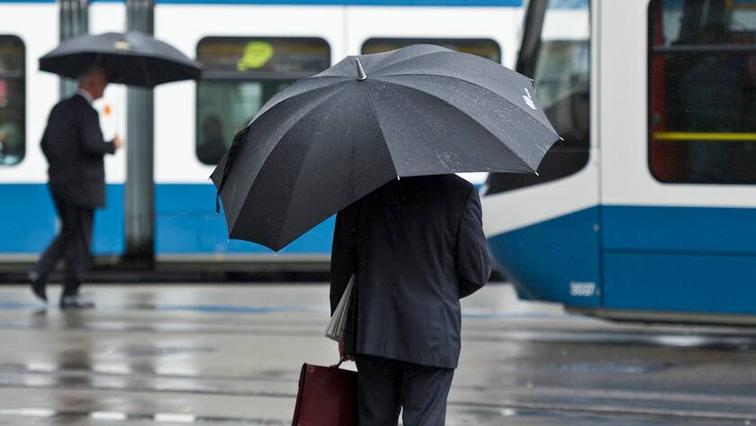 Paradeplatz Zürich: Es regnet und ein Banker wartet auf das Tram.
