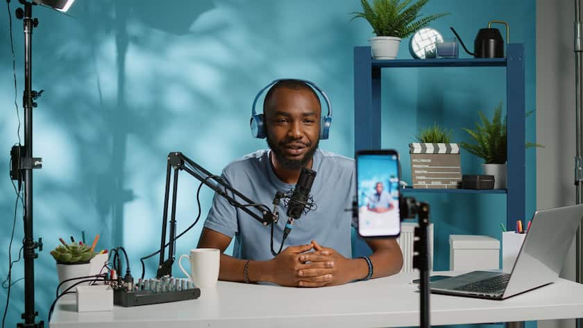 Blogger waving at smartphone camera for social media vlog. Influencer using mobile phone to record podcast for channel and subscribers. Vlogger filming video with modern equipment