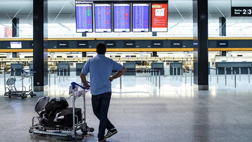 A passenger is looking at the departures board at the Zurich Airport in Zuerich, Switzerland, Tuesday, March 10, 2020. The spreading of the Coronavirus has effects on the passenger volume at Switzerland's biggest airport. (KEYSTONE/Alexandra Wey)