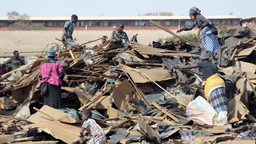 epa09285812 Women and children pick up pieces of leftovers from the demolished vending stalls in the township of Mbare, Harare, Zimbabwe,19 June 2021. The government approved the demolition of the stalls which are a source livelihood for many as there are not enough jobs in the informal sector. EPA/AARON UFUMELI