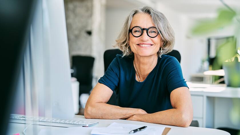 Portrait of confident mature businesswoman. Smiling female professional is working in creative office. She is wearing eyeglasses.