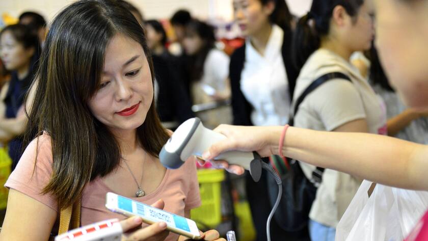 Eine Frau bezahlt an einer Kasse mit der Bezahl-App Alipay