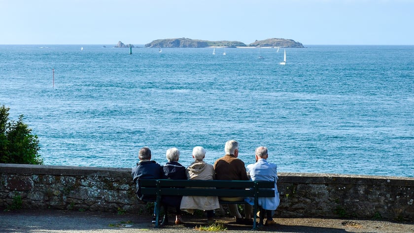 Ältere Menschen die gemeinsam am Meer sitzen.