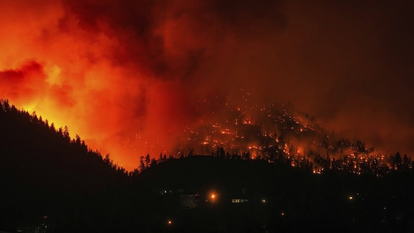 The McDougall Creek wildfire burns on the mountainside above houses in West Kelowna, B.C., on Friday, Aug. 18, 2023. Thousands have fled, driving hundreds of kilometers (miles) to safety or waiting in long lines for emergency flights, as the worst fire season on record in Canada showed no signs of easing.