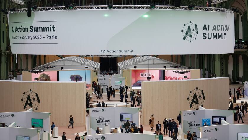 People walk between booths during the Artificial Intelligence (AI) Action Summit at the Grand Palais in Paris, France, 10 February 2025. The summit takes place from 10 to 11 February.