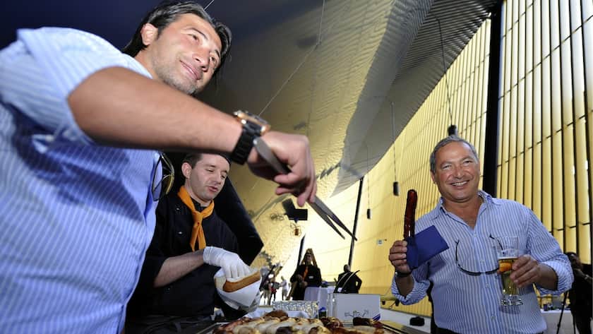 Samih Sawiris, rechts, Aktionaer der Holdinggesellschaft Loewen Sport und Event AG, die Mehrheitsaktionaerin der FC Luzern- Innerschweiz AG ist, haelt eine von FC Luzern Trainer und Grillmeister Murat Yakin, links, zubereitete Wurst in die Hoehe an einer Medienkonferenz am Donnerstag, 7. Juli 2011, in der Swissporarena in Luzern. (KEYSTONE/Sigi Tischler)
