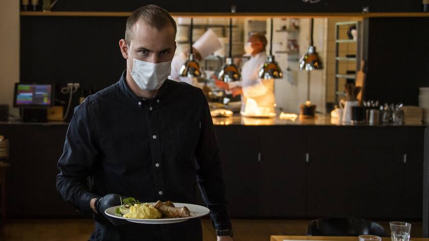 A waiter of "La Brasserie de Montbenon" restaurant brings dishes food to customers during the spread of the pandemic Coronavirus (COVID-19) disease in Lausanne, Switzerland, Monday, May 11, 2020. In Switzerland from today, the Swiss authorities lifted second part of the lockdown. (KEYSTONE/Jean-Christophe Bott)