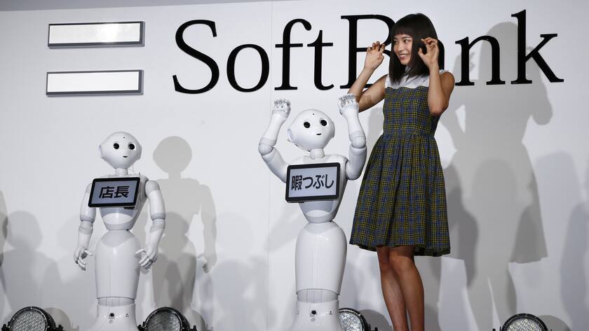 Japanese actress Suzu Hirose and SoftBank's robots Pepper pose for photographers during a media event in Tokyo, Wednesday, Jan. 27, 2016. The monitors read "store manager, left, and "killing time." (AP Photo/Shizuo Kambayashi)