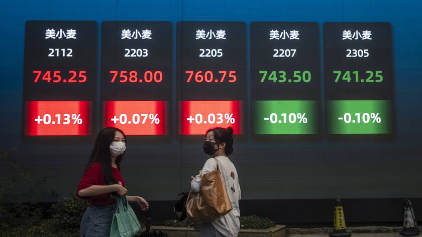 Menschen laufen vor dem Bildschirm mit den neuesten Börsen- und Wirtschaftsdaten.