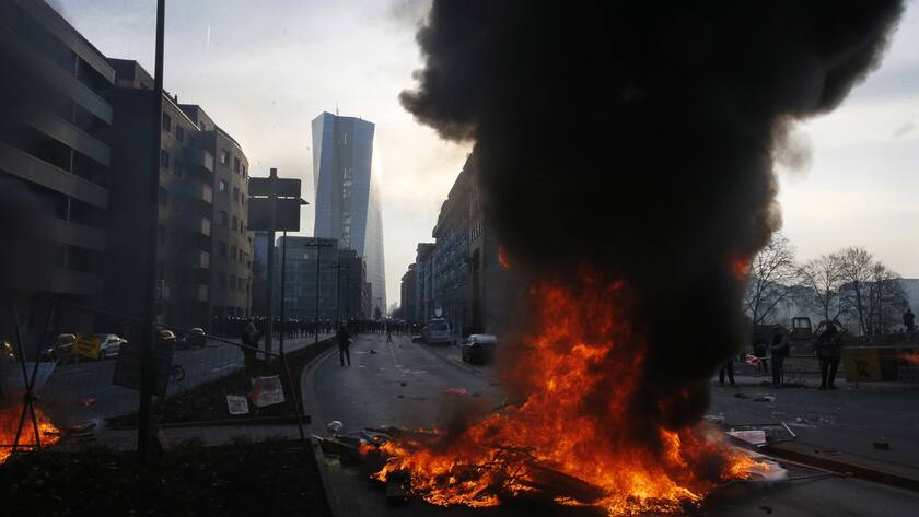 Smoke billows over burning barricades in front of the new ECB headquarters Wednesday, March 18, 2015 in Frankfurt, Germany. The Blockupy alliance said activists plan to try to blockade the new headquarters of the ECB to protest against government austerity and capitalism. (AP Photo/Michael Probst)