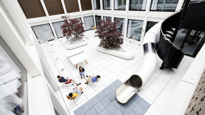 Vier Personen im Innenhof von Google in Zürich neben einer Rutsche aus der Vogelperspektive.