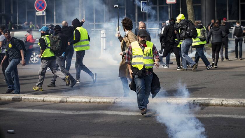 epa07489216 Protesters from the 'Gilets Jaunes' (Yellow Vests) movement run through tear gas during the 'Act XXI' demonstration (the 21st consecutive national protest on a Saturday) in Paris, France, 06 April 2019. Yellow Vest protests are expected in several cities across France. EPA/IAN LANGSDON