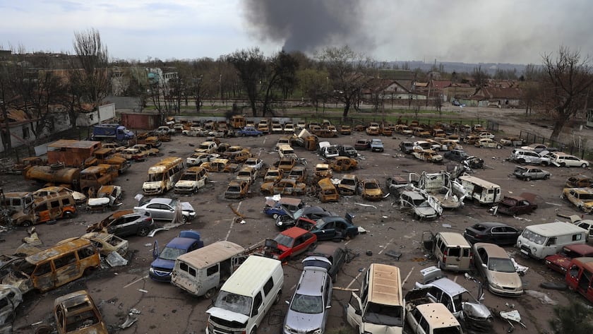 Damaged and burned vehicles are seen at a destroyed part of the Illich Iron & Steel Works Metallurgical Plant, as smoke rises from the Metallurgical Combine Azovstal during heavy fighting, in an area controlled by Russian-backed separatist forces in Mariupol, Ukraine, Monday, April 18, 2022. Mariupol, a strategic port on the Sea of Azov, has been besieged by Russian troops and forces from self-proclaimed separatist areas in eastern Ukraine for more than six weeks. (AP Photo/Alexei Alexandrov)