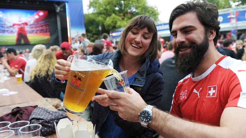 Mit Bier-Investments Rendite machen Zuschauer schenken sich Bier ein, beim Public Viewing eines EM-Spiels