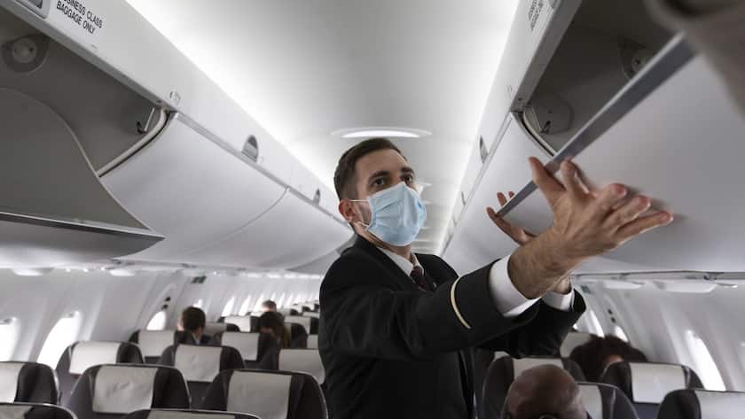 A cabin crew member of Swiss International Air Lines wearing a face mask to protect against the spread of coronavirus COVID-19 prepares the aircraft prior to departure to London during the resumption partially flights of Swiss International Air Lines following the lockdown to due lockdown measures against spread of coronavirus COVID-19, at the Geneve Aeroport, in Geneva, Switzerland, Monday, June 15, 2020. (KEYSTONE/Salvatore Di Nolfi)