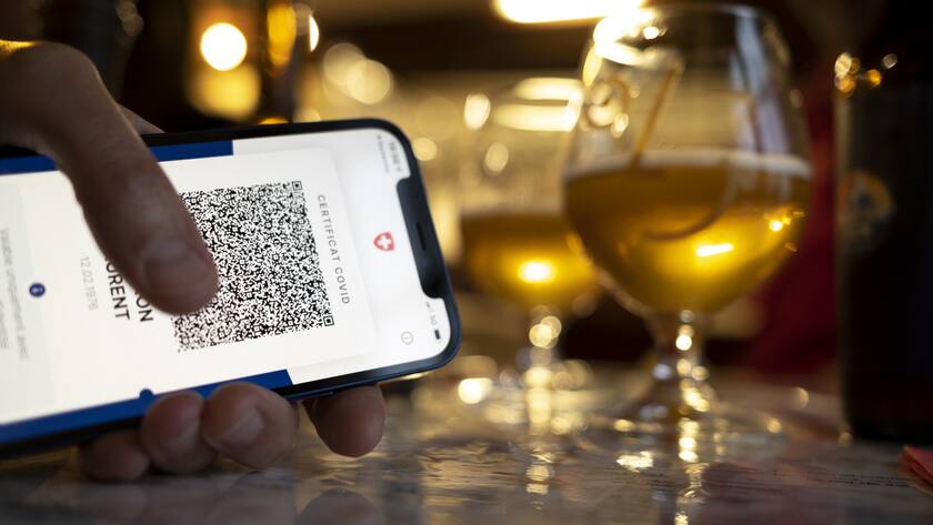 Une personne tient dans sa main un smartphone avec l'application Certifact Covid suisse dans un restaurant ce vendredi 10 septembre 2021 a Rances dans le canton de Vaud. Des ce lundi 13 septembre, il faudra montrer le code QR sur l'app ou sur papier du certificat Covid pour se rendre dans un restaurant, au cinema ou encore dans un fitness. (KEYSTONE/Laurent Gillieron)