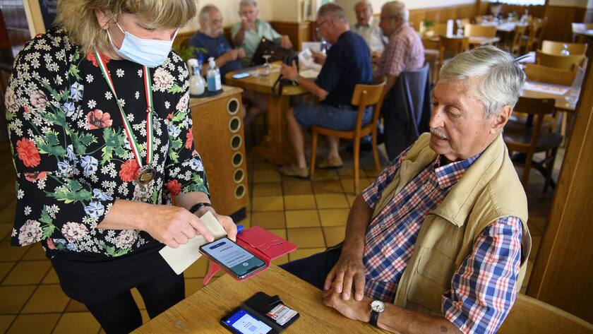 Une serveuse verifie un certificat COVID d'un client a l'aide d'un smartphone et l'application Certificat Covid Check dans le cafe restaurant de L'Europe ce lundi 13 septembre 2021 a Lausanne. Des ce lundi 13 septembre, il faut montrer le code QR sur l'app ou sur papier du certificat Covid pour se rendre dans un restaurant, au cinema ou encore dans un fitness. (KEYSTONE/Laurent Gillieron)