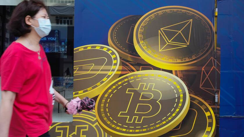FILE - In this June 1, 2021, file photo, a woman walks past an advertisement for the Bitcoin cryptocurrency in Hong Kong. ChinaâÄ™s biggest banks promised Monday, June 21, 2021, to refuse to help customers trade Bitcoin and other cryptocurrencies after the central bank said executives were told to step up enforcement of a government ban. (AP Photo/Vincent Yu, File)