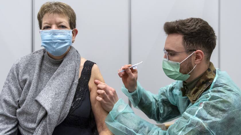 Marie Theres Domont bekommt ihre Booster-Impfung mit dem Covid-19-Impfstoff von einem Durchdienersoldaten der Sanitaetsschule Airolo im Impfzentrum in Delemont, am Dienstag, 14. Dezember 2021. (KEYSTONE/Georgios Kefalas)