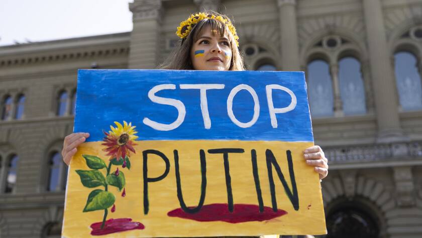 A Protester holds a "Stop Putin" banner on the Bundesplatz square during a demonstration against the Russian invasion of Ukraine in front of the Swiss parliament building in Bern, Switzerland, Saturday, March 19, 2022. (KEYSTONE/Peter Klaunzer)