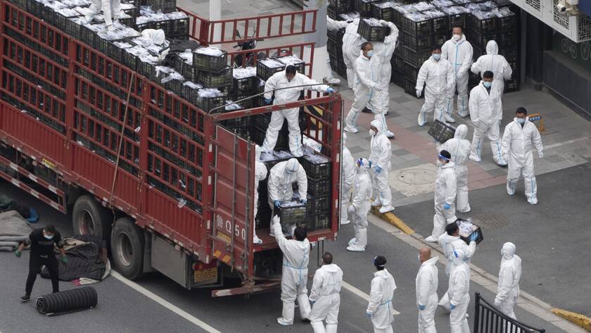 Workers in PPE unload groceries from a truck before distributing them to local residents under the COVID-19 lockdown in Shanghai, China Tuesday, April 05, 2022. The COVID-19 outbreak in China's largest metropolis of Shanghai remains "extremely grim" amid an ongoing lockdown confining around 26 million people to their homes, a city official said Tuesday. (Chinatopix Via AP) CHINA OUT